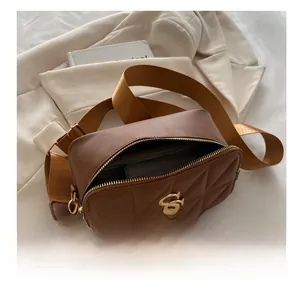 Close-up of brown quilted bag with gold S-logo, tassel detail and interior storage view