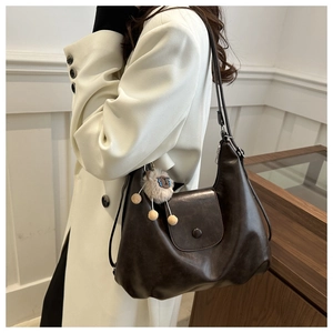 Detail view of coffee brown soft leather shoulder bag with a cute sheep plush charm