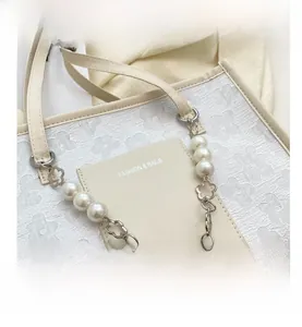 Close-up of floral texture on beige bag with pearl and silver flower chain handle