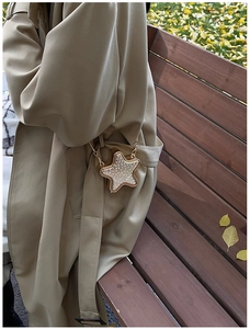 Detail of star-shaped crossbody bag with glittering rhinestones and gold chain strap