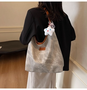Detail of grey marble canvas tote bag with brown leather trim and star plush charm