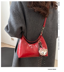 Detail of red wax leather hobo bag with glossy finish and cute brown bear plush charm