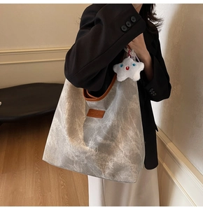 Detail of grey vintage tote bag showing wrinkled texture, leather logo, and star charm