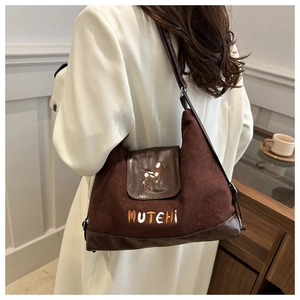 Detail of dark brown suede shoulder bag with dog embroidery and MUTEHI lettering