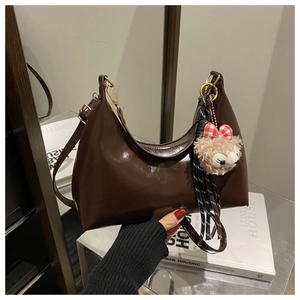 Close-up of chocolate brown patent leather hobo bag with cute teddy bear charm
