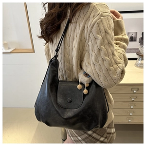 Close-up of large matte black PU leather tote bag with cute alpaca charm and metal clasp