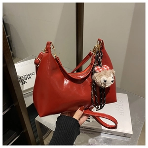 Detail of red patent leather shoulder bag with glossy finish and gold metal hardware