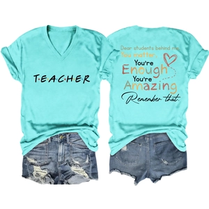 Flat lay of teacher graphic t-shirt with inspirational back text and denim shorts