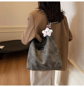 Detail of grey vintage textured tote bag featuring fashion label and star plush charm