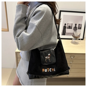 Detail of black suede tote bag featuring dog embroidery and MUTEHI logo lettering
