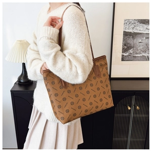 Brown monogram tote bag with leather trim and large capacity shown on model shoulder