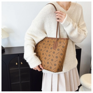 Detail of a brown leather tote bag with floral print worn as a shoulder bag