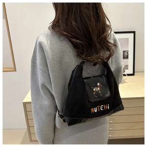 Close-up of black suede backpack with dog embroidery and Mutehi logo on adjustable straps