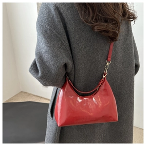 Detail of red oil wax leather dumpling bag with polished finish and gold metal hardware