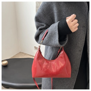 Detailed macro view of high-gloss red hobo bag with sleek finish and wax texture