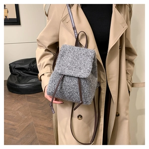Detail of grey wool-textured backpack with slim brown leather straps and drawstring