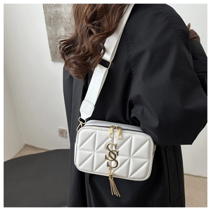 Close-up of white quilted crossbody bag featuring golden SS logo and tassel detail on strap