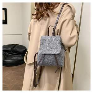 Retro grey tweed mini backpack with brown leather straps shown on a beige trench coat