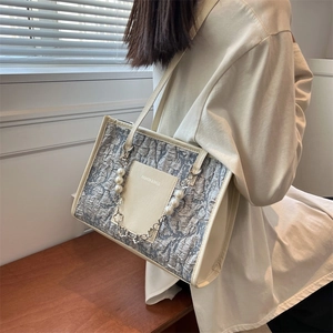 Chic grey pleated shoulder bag with pearl chain strap and floral charm on a female model