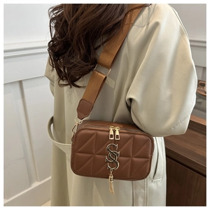Detail of vintage brown quilted crossbody bag with gold logo and stylish chain strap