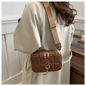 Detail of vintage brown quilted leather crossbody bag with golden hardware and tassel