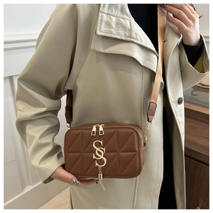 Detail of brown quilted crossbody bag featuring gold S-logo hardware and wide strap