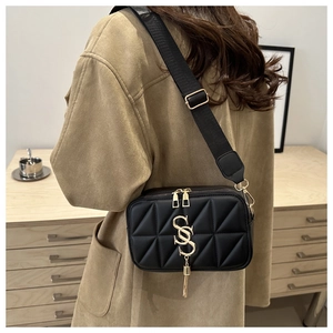 Detail of black quilted crossbody bag featuring golden double S logo and tassel pendant