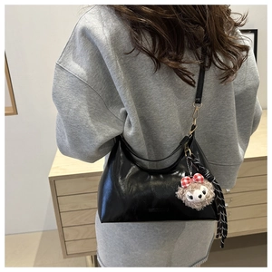Chic black oil wax leather half-moon bag with bear charm and silk scarf detail