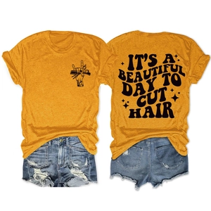 Détail du dos du t-shirt jaune montrant le texte 'IT'S A BEAUTIFUL DAY TO CUT HAIR' et motif