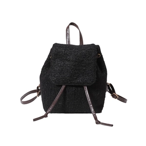 Retro-Rucksack aus schwarzem Lammfell-Imitat mit braunen Lederriemen und Metallschnalle vor weiß
