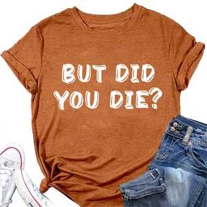 Dettaglio della maglietta arancione con stampa BUT DID YOU DIE? e nodo decorativo