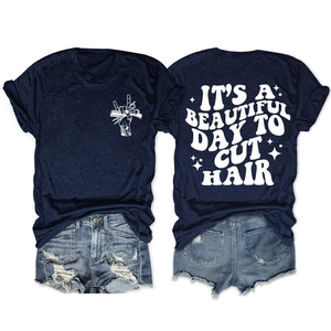 Détail de l'imprimé blanc 'IT'S A BEAUTIFUL DAY TO CUT HAIR' au dos du t-shirt bleu