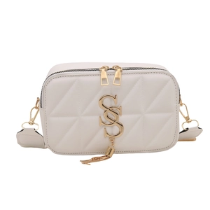 White quilted crossbody bag with gold S-logo, chain strap, and elegant metal tassels