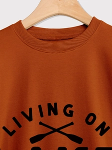 Detail of ribbed neckline and Living On text print on orange casual sweatshirt