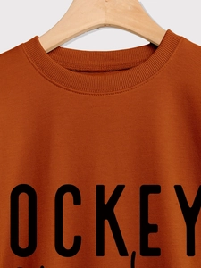 Détail de l'encolure côtelée et du logo HOCKEY sur un sweat-shirt de couleur caramel