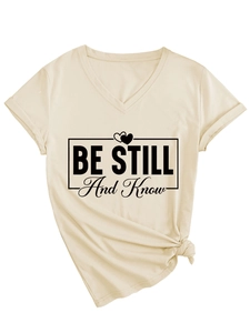 Detail of V-neck apricot tee showing BE STILL and Know print with a stylish side knot hem