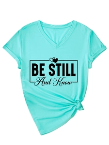 Close-up of mint green V-neck t-shirt featuring Be Still And Know print and knotted hem detail