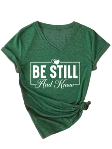 Close-up of V-neck dark green T-shirt with BE STILL print and side knot detail