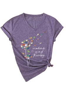 Détail du t-shirt violet col V avec pissenlit en livres et texte 'reading is my therapy' brodé