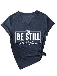 Detail of V-neck T-shirt in navy marl with BE STILL And Know quote and knotted hem