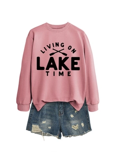 Detail of pink cotton sweatshirt with 'LIVING ON LAKE TIME' print and ripped denim shorts