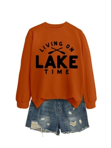 Flat lay detail of orange sweatshirt with Lake Time print and ripped denim shorts