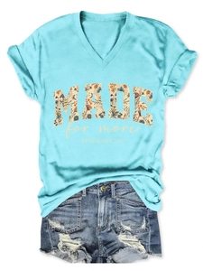 Detailed flat lay of light blue V-neck T-shirt with vintage floral 'MADE' text and denim shorts