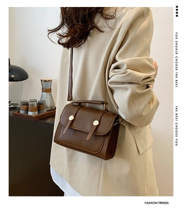 Detail of dark brown vintage satchel showing the matte texture and gold buckle hardware