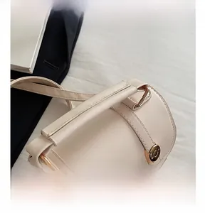 Detail of beige cylinder handbag showing sturdy handle and light gold metal rivets