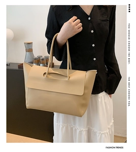 Detail of beige faux leather tote bag with flap closure and cutout handle for commuting