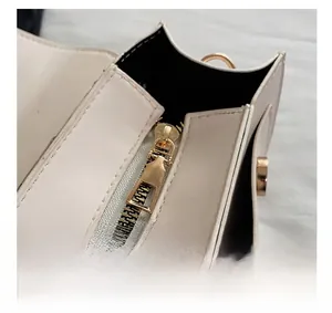 Close-up of smooth gold metal zipper detail on beige leather crossbody handbag