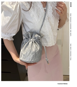 Silver bucket bag with pleated texture and drawstring closure on a model