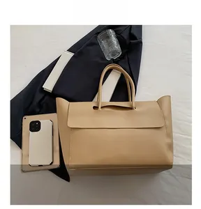 Detail view of khaki tote bag capacity showing comparison with tablet and phone