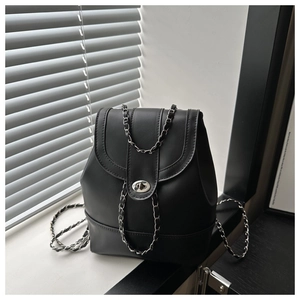 Détail d'un sac à dos en cuir noir avec bandoulière en chaîne argentée et fermoir pivotant